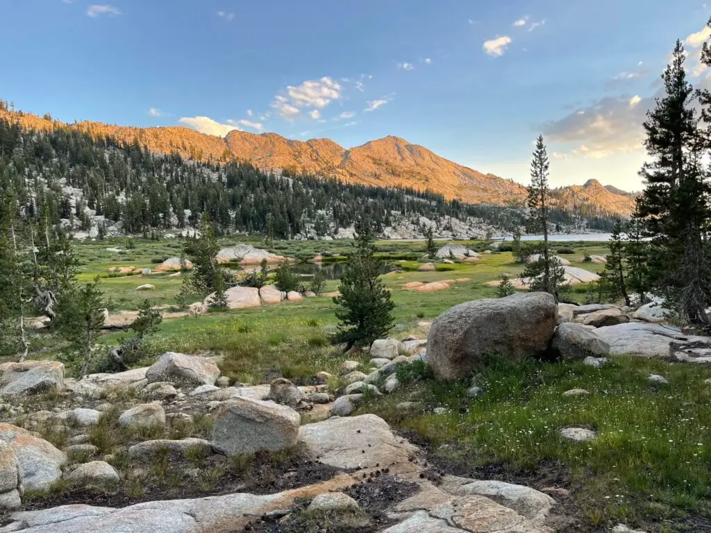 a meadow in yosemite national park, showing mountains and an alpine lake